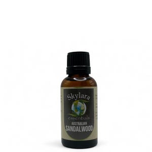 Puede incluir: Una botella de vidrio marr&oacute;n de aceite esencial de s&aacute;ndalo australiano Skylar essentials. La etiqueta presenta el nombre de la marca, un gr&aacute;fico de globo y el nombre del producto en un esquema de color marr&oacute;n oscuro y verde. La botella tiene una tapa negra.