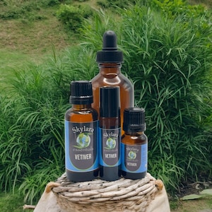 May include: Three amber glass bottles of Skylara Essentials Vetiver essential oil with black caps. The bottles feature blue labels with a globe graphic and the text Skylara Essentials Vetiver. One bottle has a dropper top, one is a roller bottle.