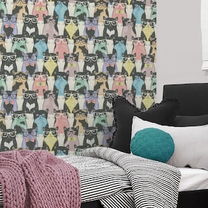 May include: A black bed frame with a white and black striped comforter and a pink knitted throw blanket. The bed is against a wall with a wallpaper featuring a repeating pattern of colorful cats wearing glasses.