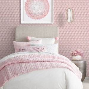 K&ouml;nnte beinhalten: Ein wei&szlig;es Bett mit einem rosa, gekr&auml;uselten Bett&uuml;berwurf und einem rosa-wei&szlig; gemusterten Kopfteil. Das Bett hat ein wei&szlig;es Kissen mit einem rosa Blumendesign und ein rosa Kissen mit einem wei&szlig;en Blumendesign. Das Bett steht in einem Zimmer mit rosa Tapete und einem wei&szlig;en gerahmten Bild einer rosa Blume.
