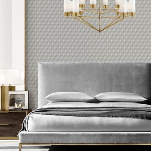 K&ouml;nnte beinhalten: Ein graues, gepolstertes Bettgestell mit einem goldenen Metallfu&szlig; und zwei wei&szlig;en Kissen. Das Bett steht in einem Schlafzimmer mit grauer, gemusterter Tapete und einem goldenen Kronleuchter mit mattierten Glasschirmen.