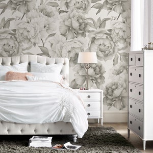 May include: A white upholstered bed with a tufted headboard and a white duvet cover. The bed is in a bedroom with a gray floral wallpaper and a white nightstand with three drawers. A gray rug is on the floor.