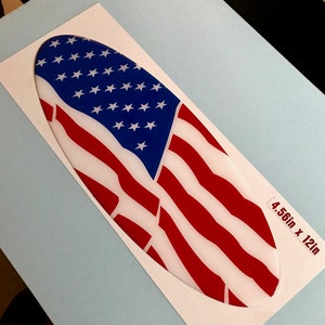 May include: Oval-shaped sticker with an American flag design. The flag is red, white, and blue with a white background. The sticker is 4.56 inches by 12 inches.
