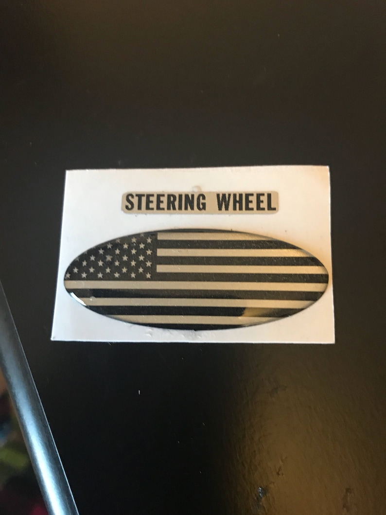 May include: A black and white American flag sticker with the words "Steering Wheel" printed above it.