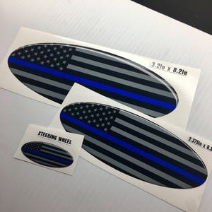 May include: Three oval-shaped decals with a thin blue line and an American flag design. The largest decal is 3.2 inches by 8.2 inches. The smallest decal is labeled "Steering Wheel".