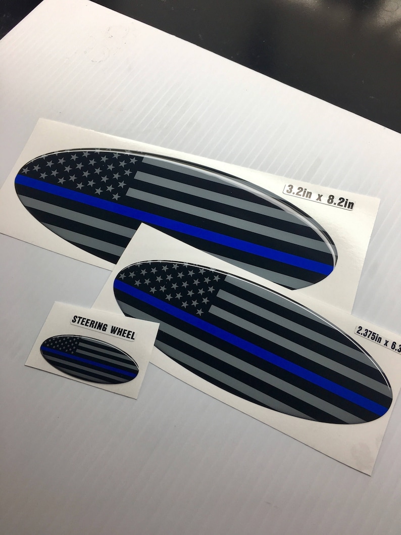May include: Three oval-shaped decals with a thin blue line and an American flag design. The largest decal is 3.2 inches by 8.2 inches. The smallest decal is labeled "Steering Wheel".
