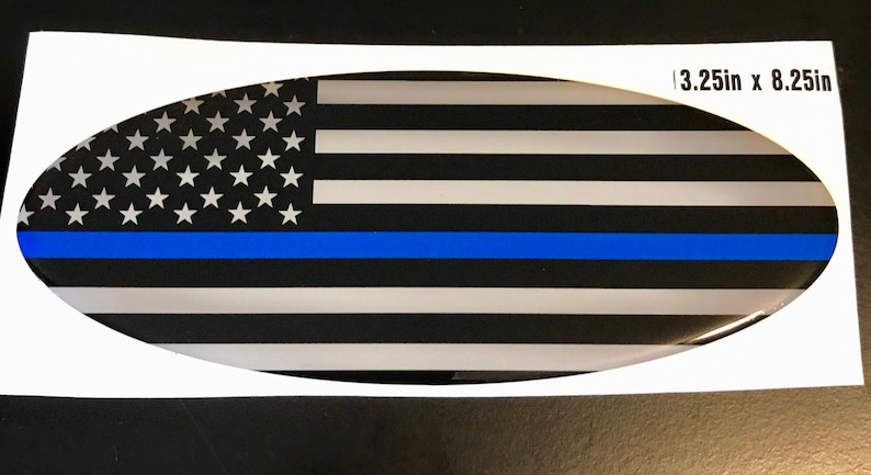 May include: Oval-shaped car decal with a black and white American flag design with a thin blue line across the middle. The decal measures 3.25 inches by 8.25 inches.