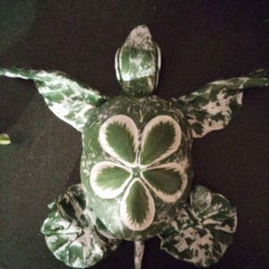 May include: A green and white turtle figurine with a five-leaf clover design on its shell.