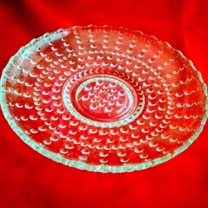 May include: A clear glass plate with a raised, textured surface of small, round bumps. The plate has a smaller, concentric circle in the center.