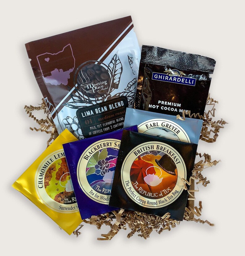 K&ouml;nnte beinhalten: Eine Sammlung von Tee- und Kaffees&auml;ckchen in verschiedenen Geschmacksrichtungen, darunter Earl Grey, English Breakfast, Brombeer-Salbei, Kamille-Zitrone und Limabohnen-Mischung. Die S&auml;ckchen sind auf einem Bett aus braunem, zerknittertem Papier angeordnet.