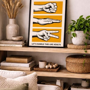 May include: A framed rectangular wall art print featuring three horizontal yellow panels, each displaying a black and white illustration of a hand gesture representing rock, paper, and scissors. The text LET'S HANDLE THIS LIKE ADULTS is printed in black at the bottom.