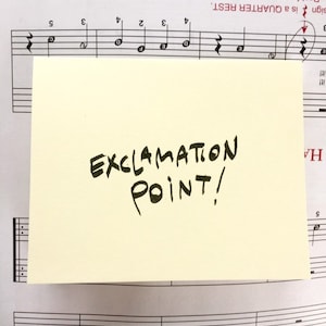 May include: A yellow sticky note with the handwritten text "EXCLAMATION POINT!" on a sheet of music.