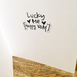 May include: A white card with black ink that says "Lucky Me Happy Vday!" with two hearts.