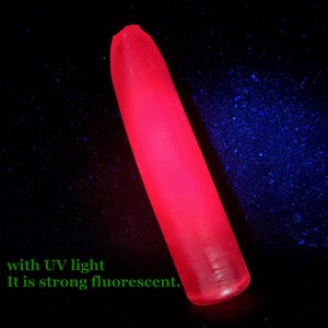 Può includere: Un oggetto rosso allungato e luminoso su uno sfondo scuro con macchie blu. Il testo nell'immagine recita: "with UV light It is strong fluorescent."