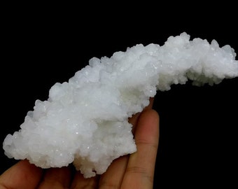 Op de afbeelding: Een wit, kristallijn mineraalspecimen met een delicate, vertakte structuur. Het mineraal lijkt een cluster van kleine, witte kristallen te zijn die samen zijn gegroeid in een uniek en ingewikkeld patroon.