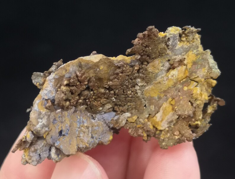 Pu&ograve; includere: Primo piano di una roccia ruvida di forma irregolare con una miscela di colori marroni, gialli e blu. La roccia ha una superficie stratificata e testurizzata.