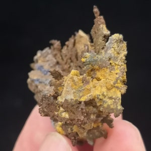 Pu&ograve; includere: Un ammasso di cristalli di rame con un'abitudine di crescita dendritica e ramificata. I cristalli sono di un mix di colori marrone, giallo e grigio.
