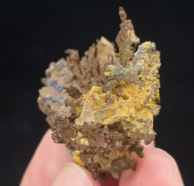 Pu&ograve; includere: Un ammasso di cristalli di rame con un'abitudine di crescita dendritica e ramificata. I cristalli sono di un mix di colori marrone, giallo e grigio.