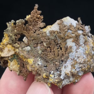 Pu&ograve; includere: Un ammasso di cristalli di rame con una superficie ruvida e testurizzata. I cristalli sono di un colore marrone rossiccio intenso e hanno un bagliore metallico. L'ammasso &egrave; circondato da una matrice di roccia bianca e grigia.