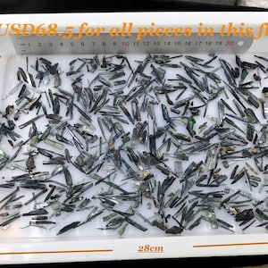 May include: A white tray containing many small, dark blue-green crystals. The tray is 28 cm by 20 cm. The image includes text that reads "USD68.5 for all pieces in this flat."