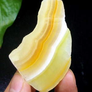 May include: A yellow, white, and orange banded agate stone with a smooth, polished surface.