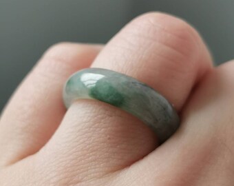 May include: A jade ring with a light green and white color. The ring is made of a smooth, polished stone.