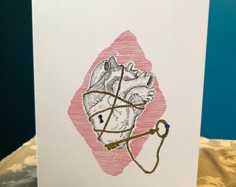 May include: A white card with a red diamond shape in the center. Inside the diamond is a black and white illustration of a heart tied with rope and a key. The key is gold and has a blue ring on the end.