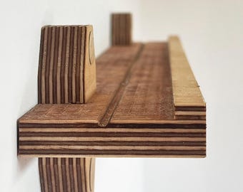 Peut inclure: Une étagère en bois avec une finition en bois naturel et une construction en couches. L'étagère est fixée à un mur avec deux supports en bois.