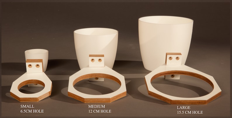 May include: Three white ceramic plant pots with wooden wall mounts. The pots are labeled "Small 6.5cm Hole", "Medium 12cm Hole", and "Large 15.5cm Hole".