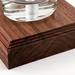 May include: A square wooden base with a dark brown finish. The base has a beveled edge and a smooth surface.