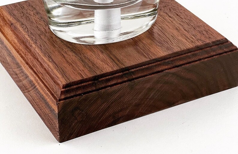 May include: A square wooden base with a dark brown finish. The base has a beveled edge and a smooth surface.