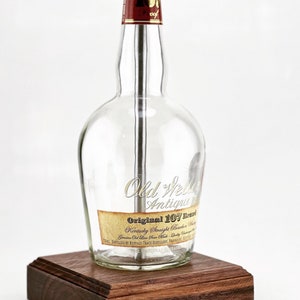 May include: A lamp made from a clear glass bottle with a wooden base. The bottle is labeled "Old Weller Antique Original 107 Brand Kentucky Straight Bourbon Whiskey".