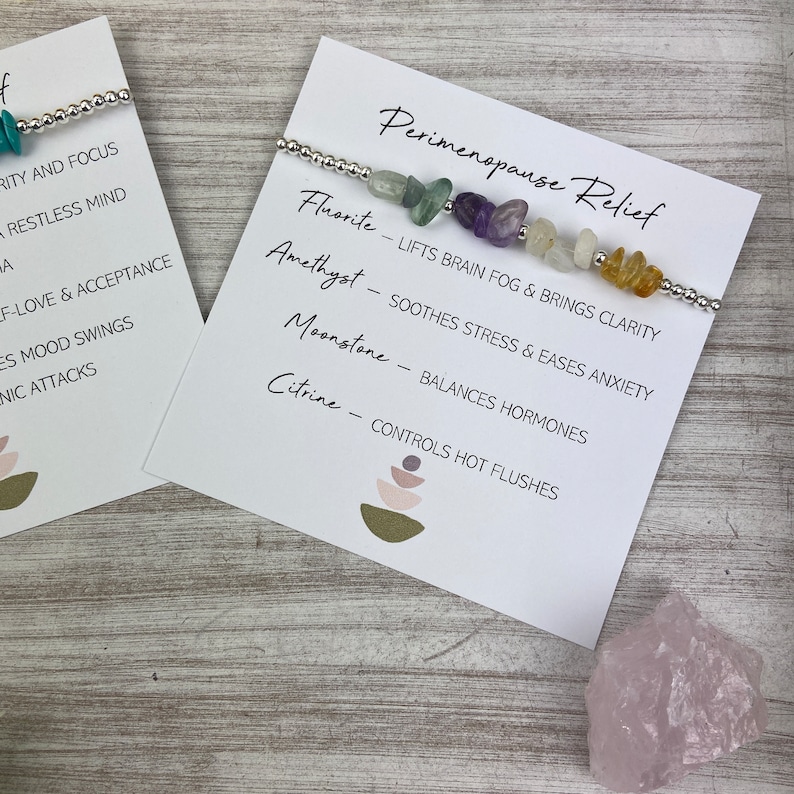 May include: A silver bracelet with various colored gemstones, including amethyst, fluorite, moonstone, and citrine. The bracelet is displayed on a white card with the text "Perimenopause Relief" and descriptions of the gemstones' benefits.