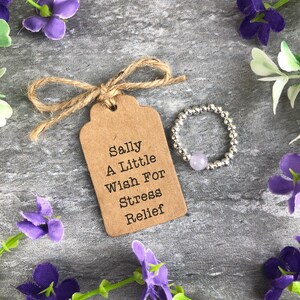 May include: A silver beaded ring with a light purple stone, packaged with a brown gift tag that reads "Sally A Little Wish For Stress Relief".