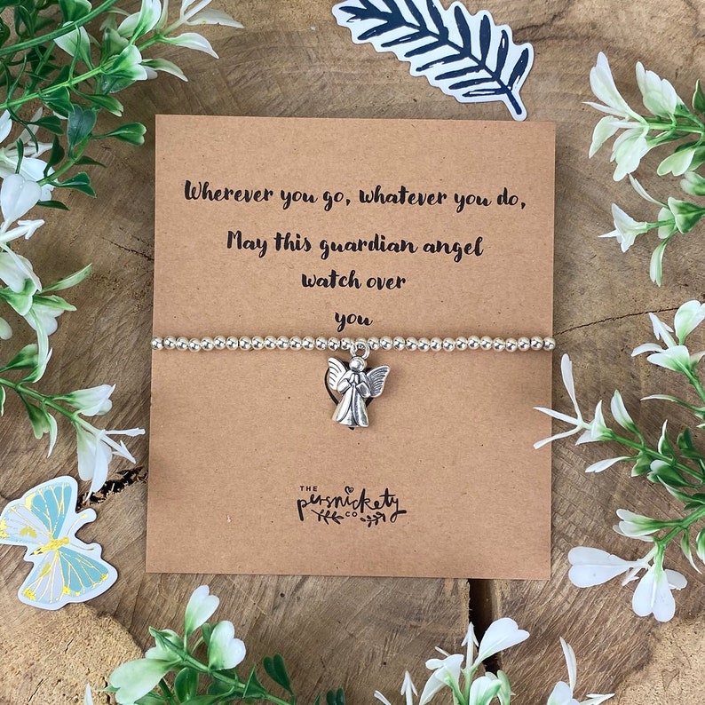 May include: A silver charm bracelet with an angel charm. The bracelet is on a card with the text "Wherever you go, whatever you do, May this guardian angel watch over you".