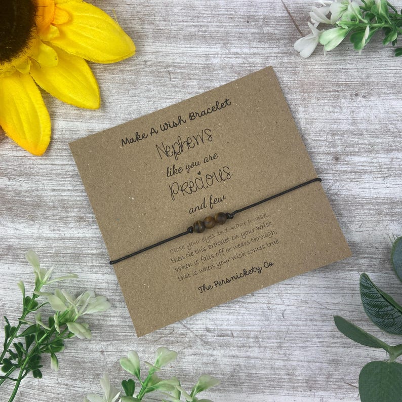 May include: A brown card with the text "Make A Wish Bracelet" and "Nephews like you are Precious and few". The card has a brown string bracelet with brown beads attached.