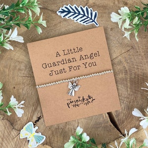 May include: A silver charm bracelet with an angel charm. The bracelet is on a card that says "A Little Guardian Angel Just For You" and "The Punsnickety Co."