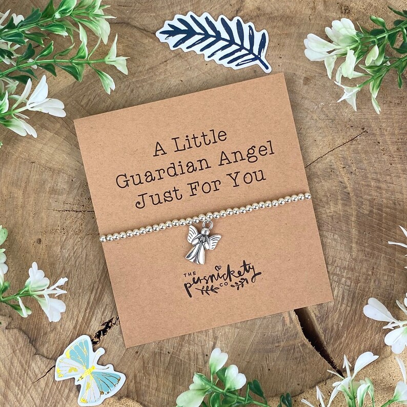 May include: A silver charm bracelet with an angel charm. The bracelet is on a card that says "A Little Guardian Angel Just For You" and "The Punsnickety Co."