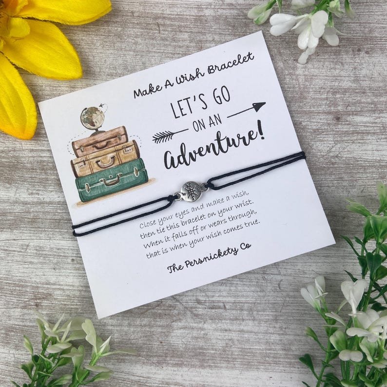 May include: A wish bracelet with a black cord and a silver charm, presented on a card with the text "Make A Wish Bracelet" and "Let's Go On An Adventure!". The card also includes instructions and the brand name.