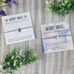 May include: Two cards with the text "Worry Angel" and a silver angel charm bracelet on each card. The text on the cards reads "Here's a little worry angel just for you". The text on the first card reads "Wear her every day and she will love and protect you whenever you feel anxious". The text on the second card reads "When you are feeling low or anxious just remember she is here for you. Tell her your worries and she will help calm you."