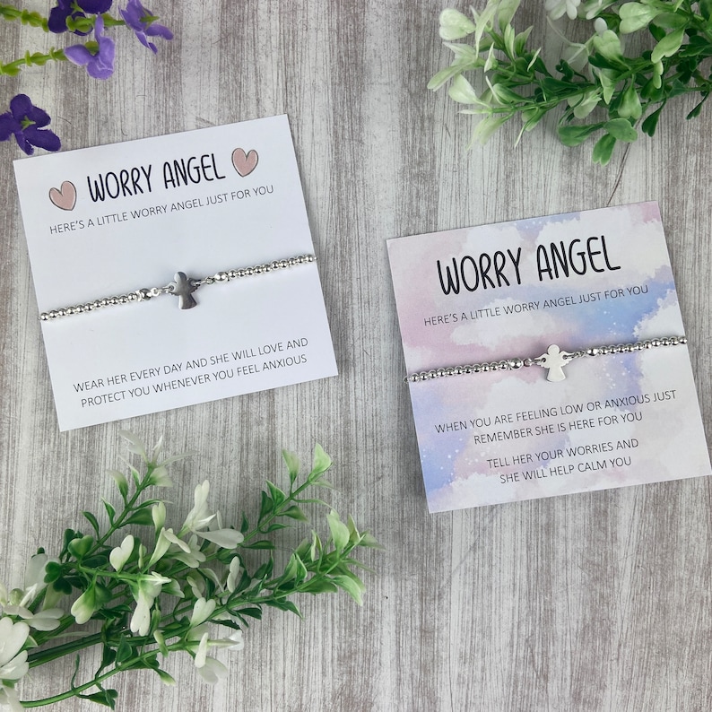 May include: Two cards with the text "Worry Angel" and a silver angel charm bracelet on each card. The text on the cards reads "Here's a little worry angel just for you". The text on the first card reads "Wear her every day and she will love and protect you whenever you feel anxious". The text on the second card reads "When you are feeling low or anxious just remember she is here for you. Tell her your worries and she will help calm you."