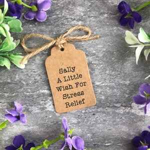 May include: A brown paper gift tag with a twine bow, featuring the text "Sally A Little Wish For Stress Relief".