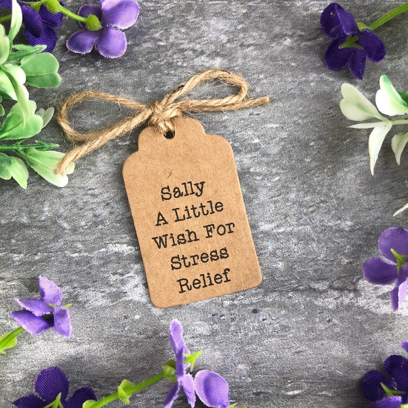 May include: A brown paper gift tag with a twine bow, featuring the text "Sally A Little Wish For Stress Relief".