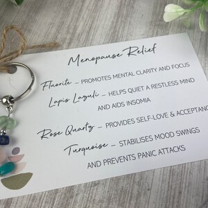 Op de afbeelding: Een witte kaart met de tekst "Menopause Relief" en een lijst met kristallen en hun voordelen voor de menopauze. De kristallen zijn fluoriet, lapis lazuli, rozenkwarts en turquoise.