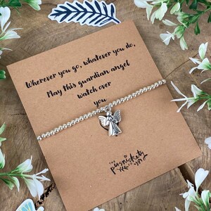 May include: A silver beaded bracelet with a small silver angel charm. The bracelet is on a brown card with the text "Wherever you go, whatever you do, May this guardian angel watch over you" and the text "THE persnickety"
