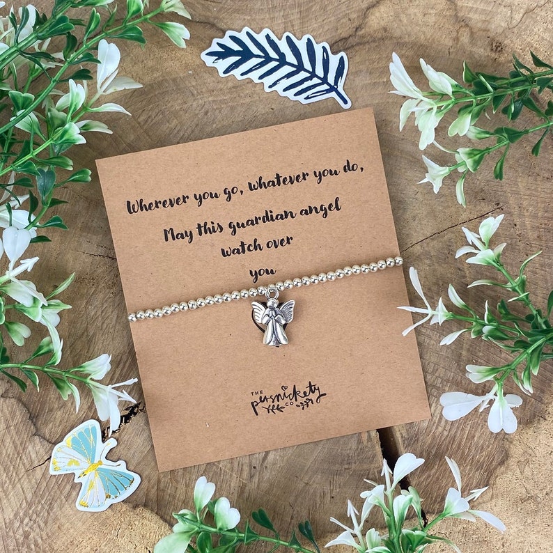 May include: A silver charm bracelet with an angel charm. The bracelet is on a brown card with the text "Wherever you go, whatever you do, May this guardian angel watch over you".