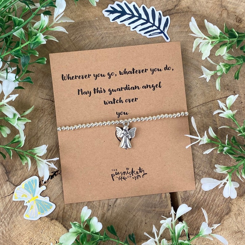 May include: A brown card with the text "Wherever you go, whatever you do, May this guardian angel watch over you."  A silver charm bracelet with an angel charm is on top of the card. The card has the text "THE  P  U  S  H  N  I  C  K  E  T  Y  CO" at the bottom.