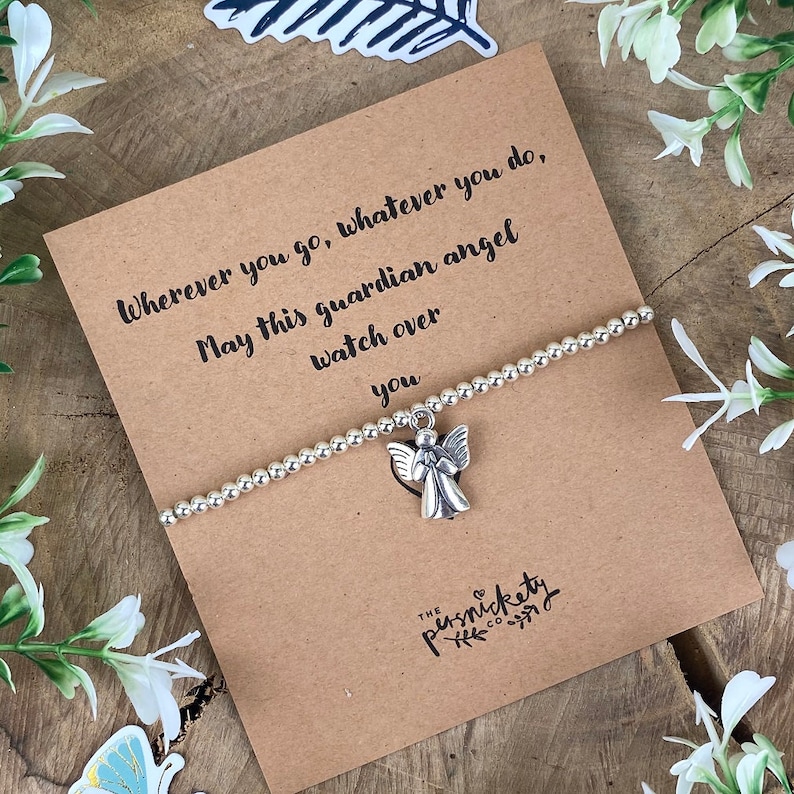 May include: A silver charm bracelet with an angel charm. The bracelet is on a card with the text "Wherever you go, whatever you do, May this guardian angel watch over you".