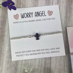 May include: A silver bracelet with a small black angel charm. The bracelet comes with a card that reads "Worry Angel" and "Here's a little worry angel just for you. Wear her every day and she will love and protect you whenever you feel anxious."