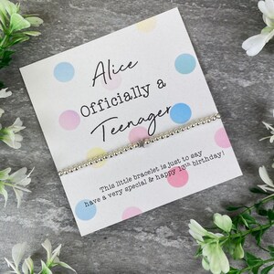 May include: A white card with colorful polka dots and the text "Alice Officially a Teenager" with a silver beaded bracelet with a star charm. The card says "This little bracelet is just to say have a very special & happy 18th birthday!"